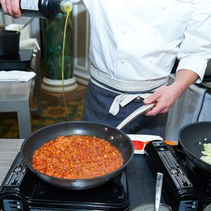 Chef Louis Simard adding olive oil to a simmering pot of veggies for his Egg Shakshuka